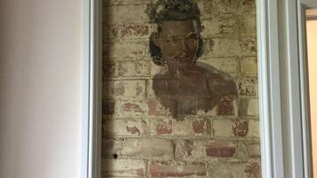 A framed portrait of a person on a brick wall.