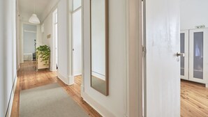 Un pasillo con piso de madera, un espejo grande y una puerta con placa de número.