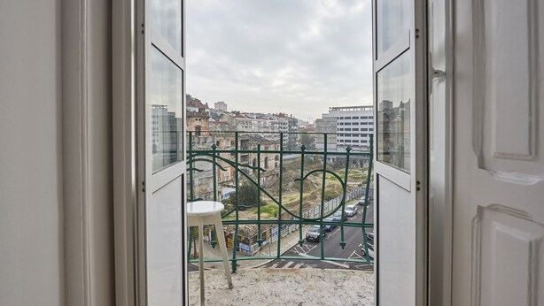Vista desde un balcón con barandilla metálica, con vistas a una calle con edificios y coches.