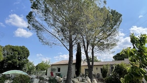 A house with a tiled roof, surrounded by a garden with large rocks and trees.