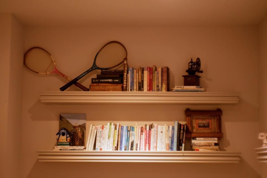 A bookshelf with books and two tennis rackets.