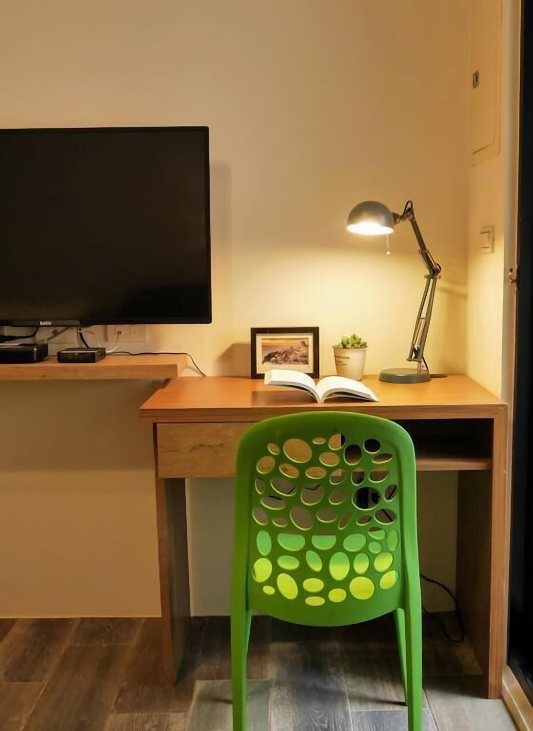 A desk with a TV, a lamp, and a chair.