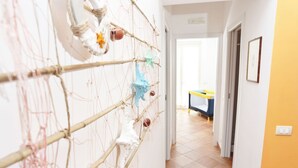 A hallway with a netted wall decoration and a blue and yellow table in the distance.