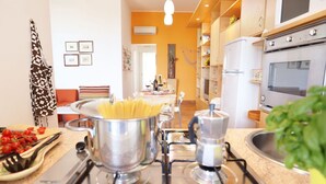 A kitchen with a stove, pots, and a dining area with chairs and a table.