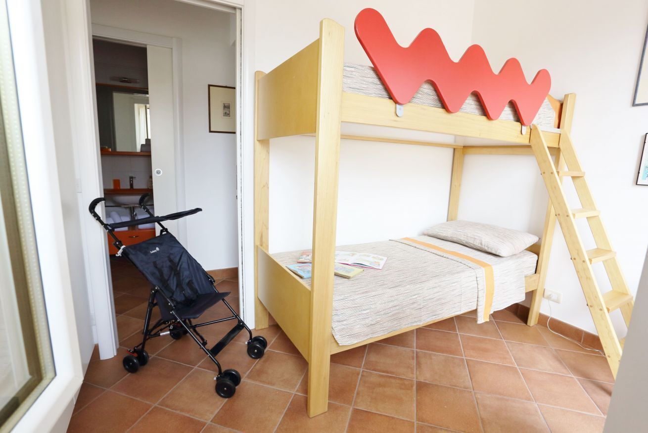 A bunk bed with a red heart-shaped decoration on top, a stroller, and a wooden ladder.