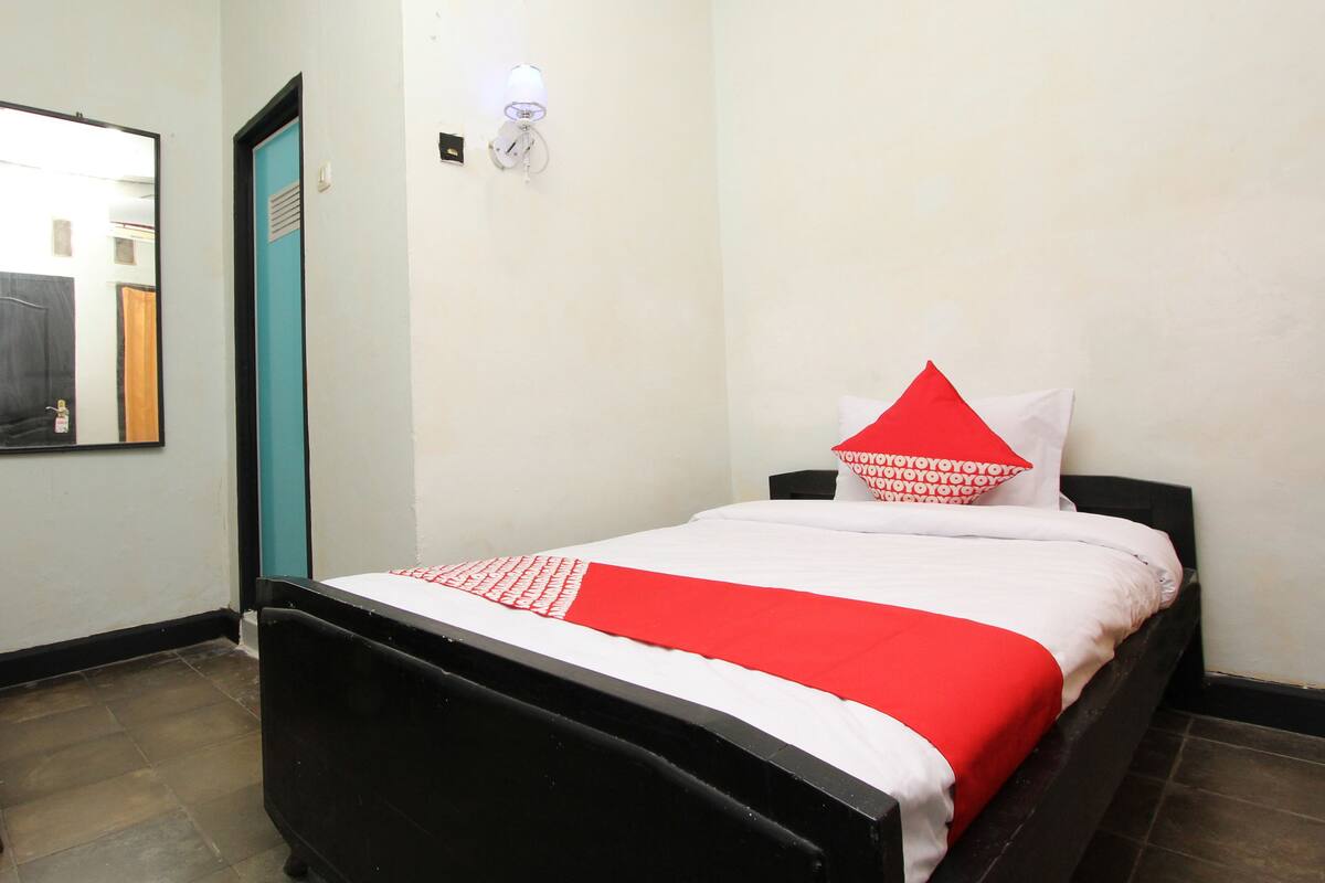 Ein Hotelzimmer mit Bett, Tür, Wandleuchte und Spiegel.