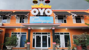 A hotel named OYO with a Parahiyangan sign, featuring a crown logo, and multiple potted plants in front.