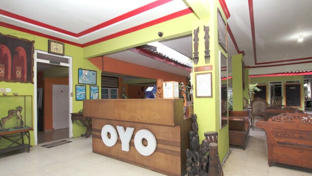 A reception area with a wooden counter labeled "OYO" and traditional wooden furniture.