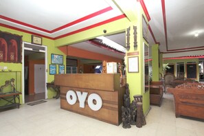 Un espace d’accueil doté d’un comptoir en bois portant l’inscription « OYO » et de meubles traditionnels en bois.