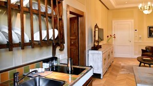Eine Küche mit einem modernen Spülbecken, einem Holzgeschirrhalter, einem weißen Schrank und einer Kandelaberleuchte.