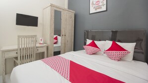 Une chambre à coucher avec un lit, un bureau, une armoire et un téléviseur.