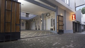 L’entrée d’un hôtel moderne, avec un sol à motifs géométriques, une porte en bois et un panneau lumineux au néon.