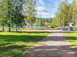 Un chemin de gravier mène à un lac, et une voiture est garée à proximité.
