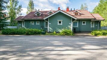A two-story house with a red-tiled roof, green siding, and a front driveway.