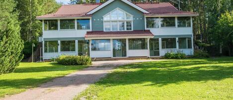 A two-story house with a red-tiled roof, large windows, and a front porch.