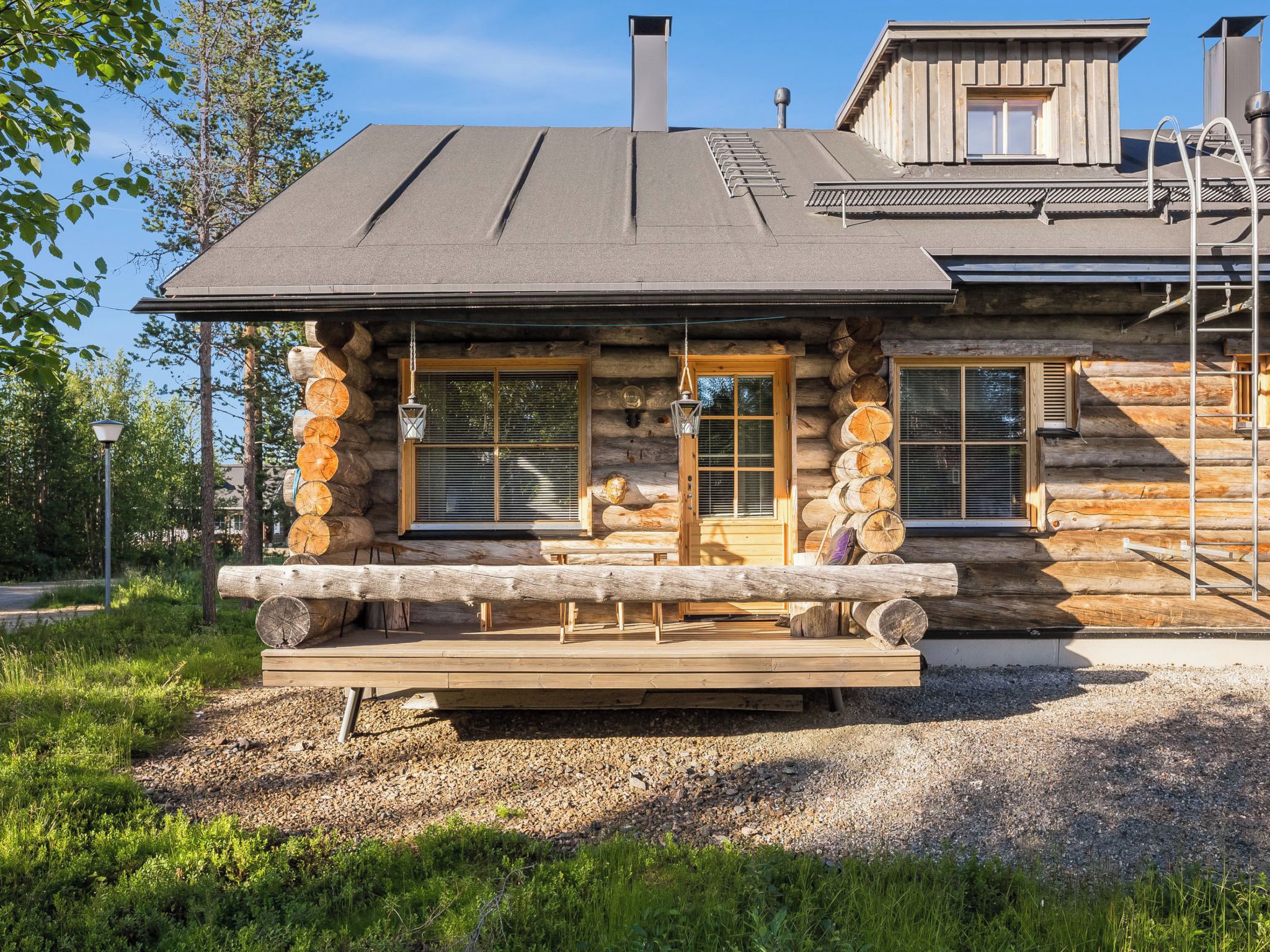 A log cabin with a wooden deck, large windows, and a chimney.