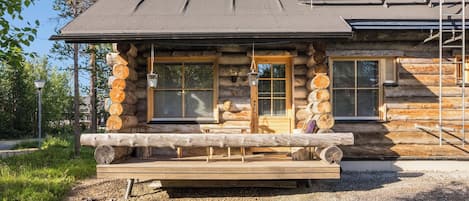 Una baita di legno con veranda, ampie finestre e un camino.