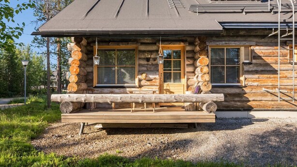 A log cabin with a wooden deck, large windows, and a chimney.