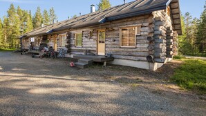 A log cabin with a gravel driveway, wooden steps, and a bicycle parked outside.