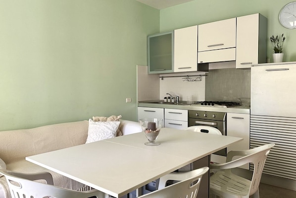 A compact kitchen with white cabinets, a dining table, and a sofa.