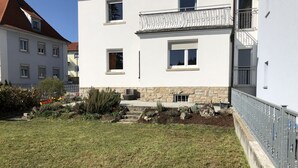 Un bâtiment à deux étages, avec une base en pierre et des murs supérieurs blancs, doté de nombreuses fenêtres et d’un balcon avec des balustrades en métal.