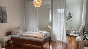 Une chambre à coucher avec un lit, un bureau, une chaise, une télévision et une plante.