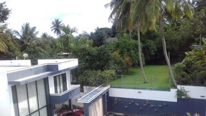 A modern building with a car parked in front, surrounded by lush greenery and palm trees. - Royal Mansions Grand Luxury Villas (Kandy)