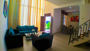 A spacious living area with a sofa set, a coffee table, and a staircase leading to another room. - Royal Mansions Grand Luxury Villas (Kandy)