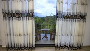 A room with a balcony, a table, and chairs. - Royal Mansions Grand Luxury Villas (Kandy)