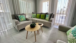 Una sala de estar moderna con dos sofás, una mesa de centro y un florero con flores.