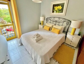A bedroom with a bed, nightstands, a lamp, a picture frame, and a view of the outdoors. - Amazing Ocean View Apartment steps from the beach  (quarteira)
