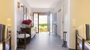 A hallway with a wooden chair, a small table with a vase of flowers, and a door leading to a balcony. - El Dorado Playa - Villa La Roca by Interhome (Cambrils)