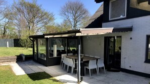 A patio area with a table and chairs, a covered seating area, and a view of the backyard. - In nature, close to the city (Aabenraa)