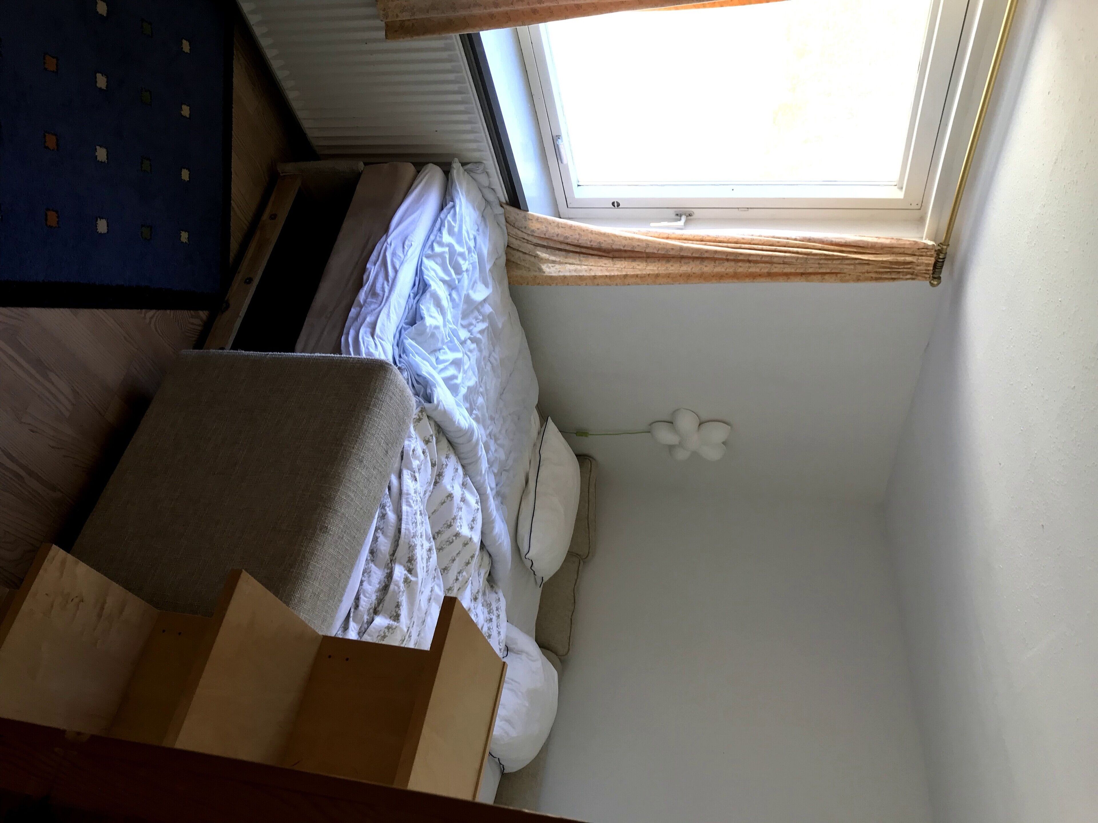 A bedroom with a bed, a window, and a small white flower decoration.