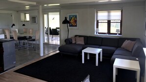 A modern living room with a grey sofa, a white coffee table, and a dining area with a table and chairs. - In nature, close to the city (Aabenraa)