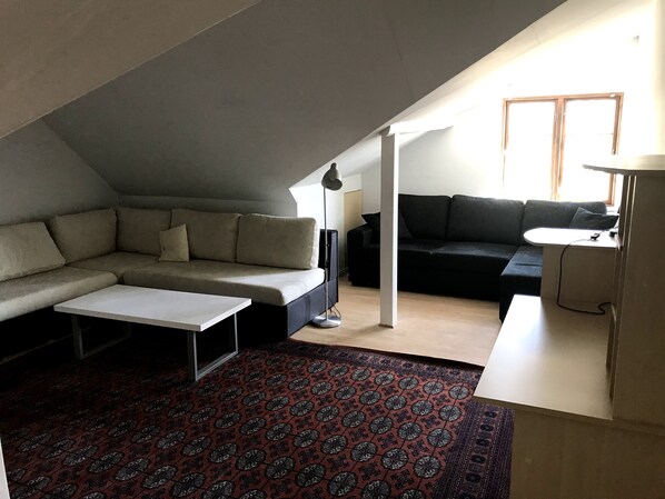 A modern loft-style living room with a sectional sofa, a small table, and a black couch. - In nature, close to the city (Aabenraa)