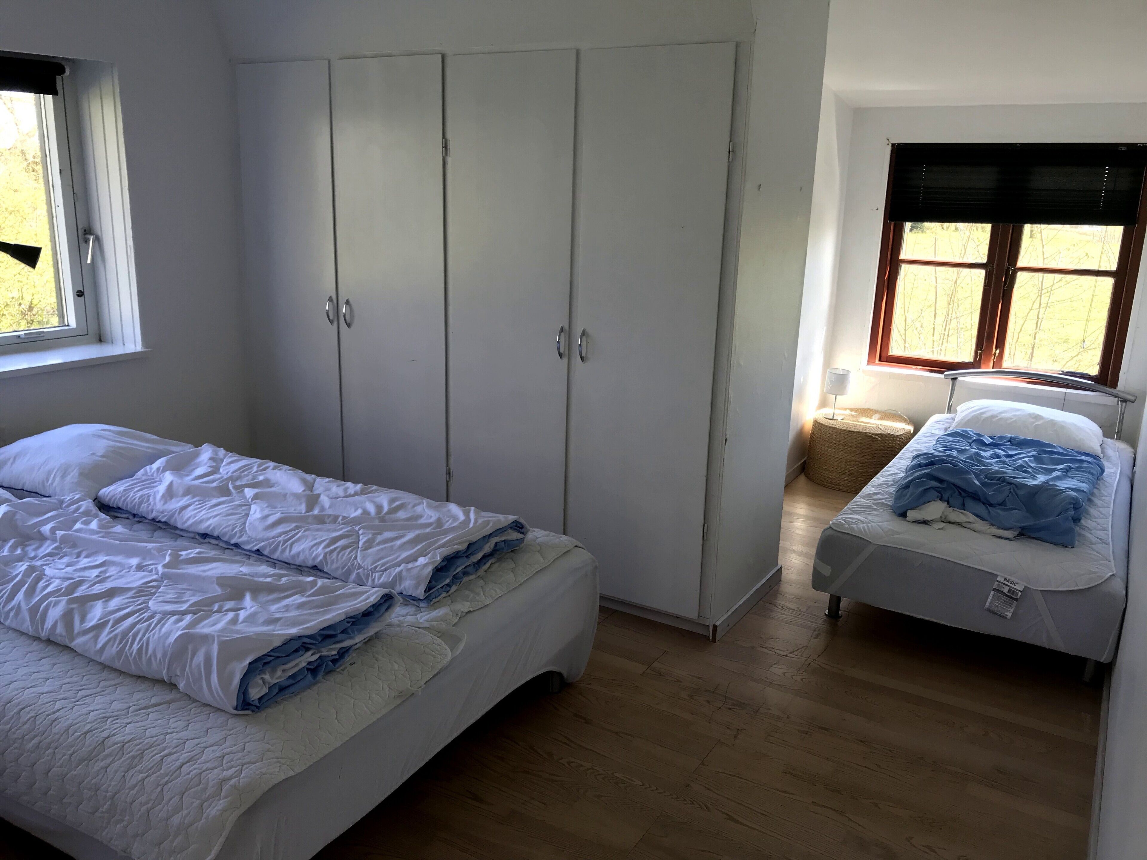 Un dormitorio con dos camas, un armario y una ventana.
