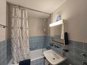 Une salle de bain avec une baignoire, un lavabo, une douche et un miroir.
