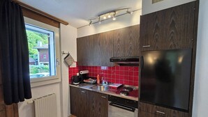 Una cuina moderna amb armaris de fusta fosca, un frigorífic d'acer inoxidable, forn integrat i salabost d'estil vermell.