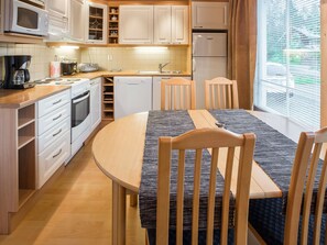 A compact kitchen with white cabinets, a microwave, a coffee maker, and a refrigerator.