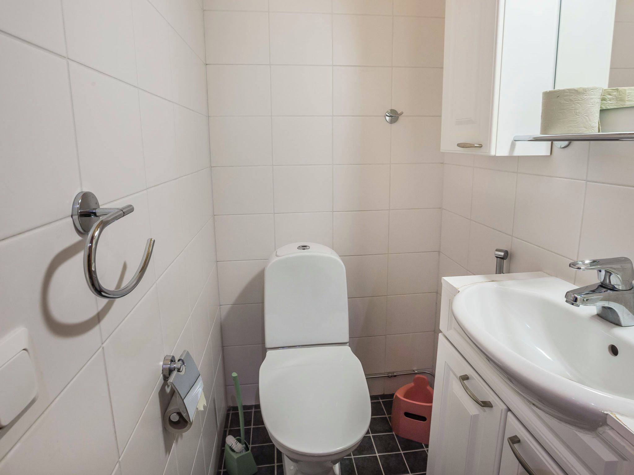 A small bathroom with a toilet, sink, and a towel rack.