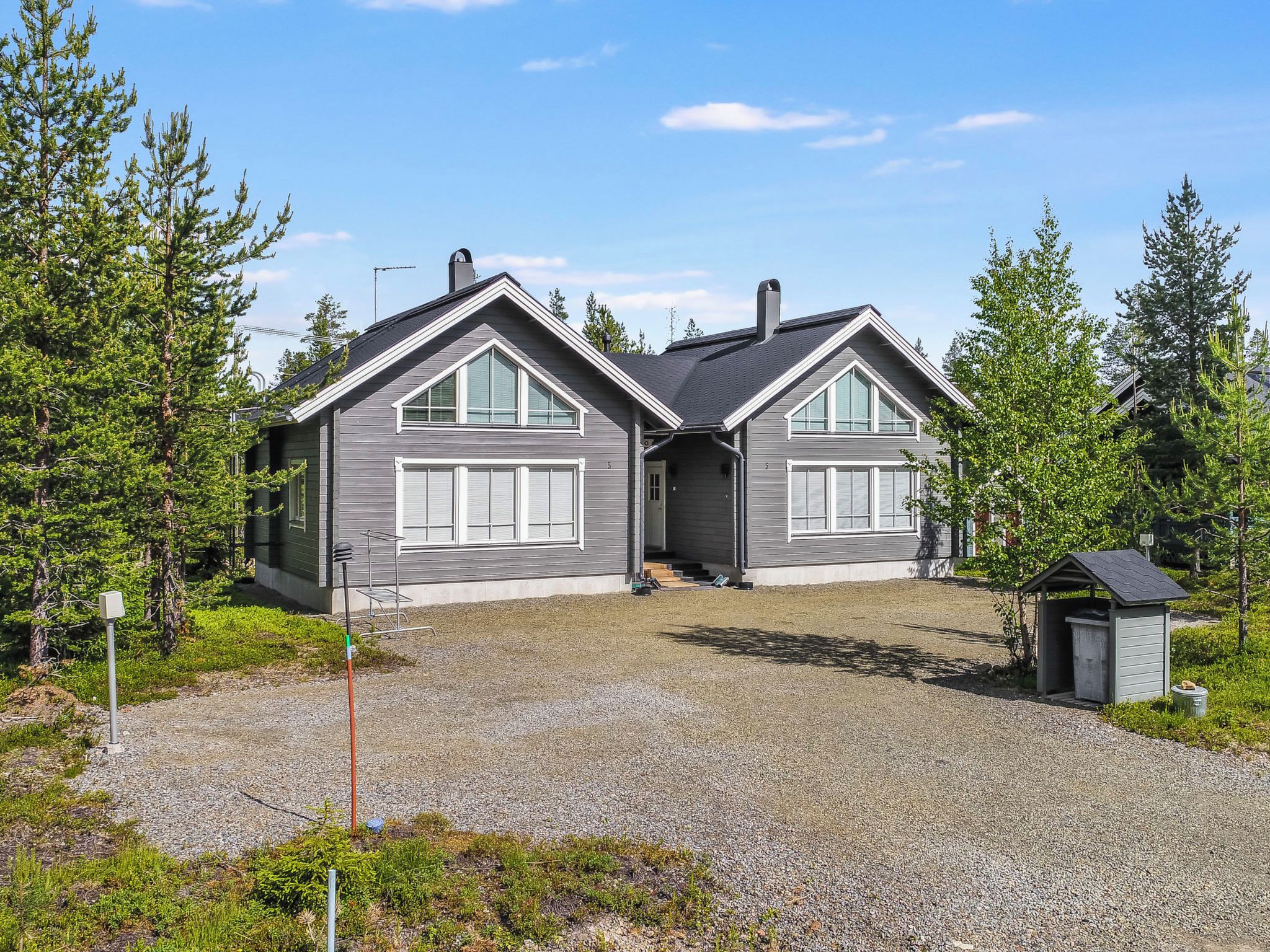 A two-story house with a gravel driveway and a small shed.