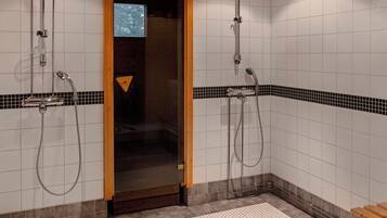 Une salle de bain avec deux douches, une porte en bois et un sol carrelé.