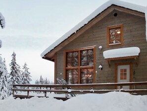 A wooden cabin with a large window, a door, and a snow-covered roof. - Kivalonmaa a by Interhome (Äkäslompolo)