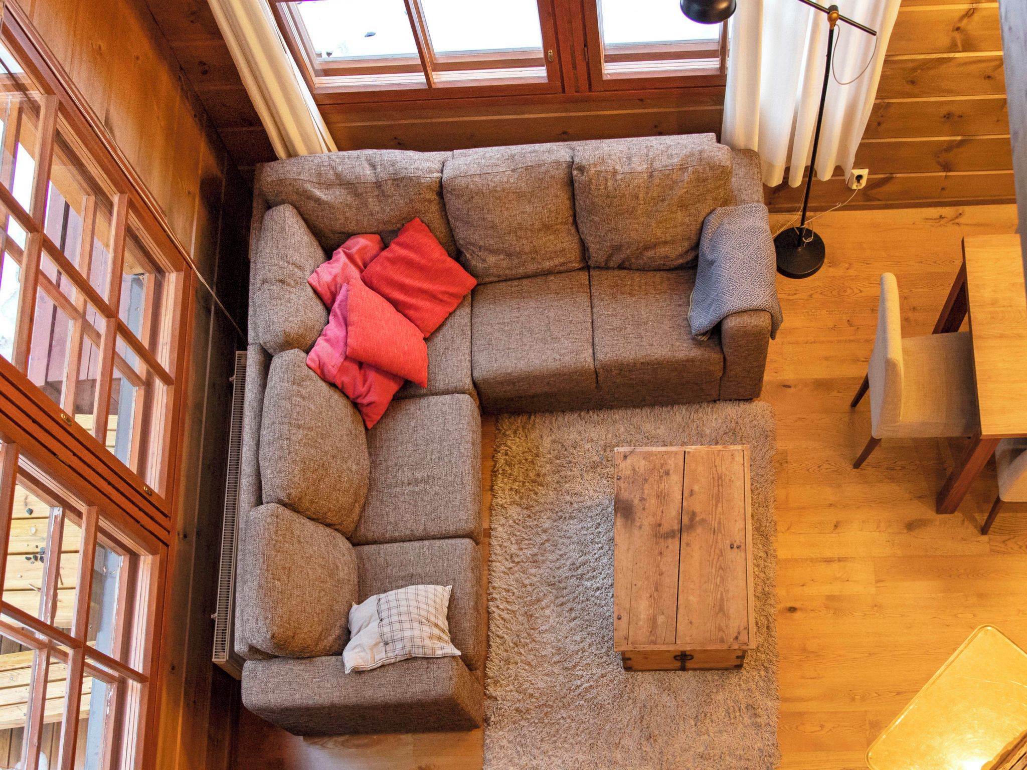 A cozy room with a sectional sofa, a small wooden table, and a view through a skylight.