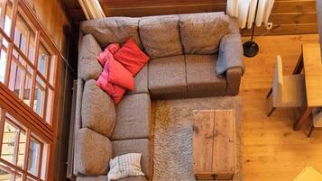 A cozy room with a sectional sofa, a small wooden table, and a view through a skylight.