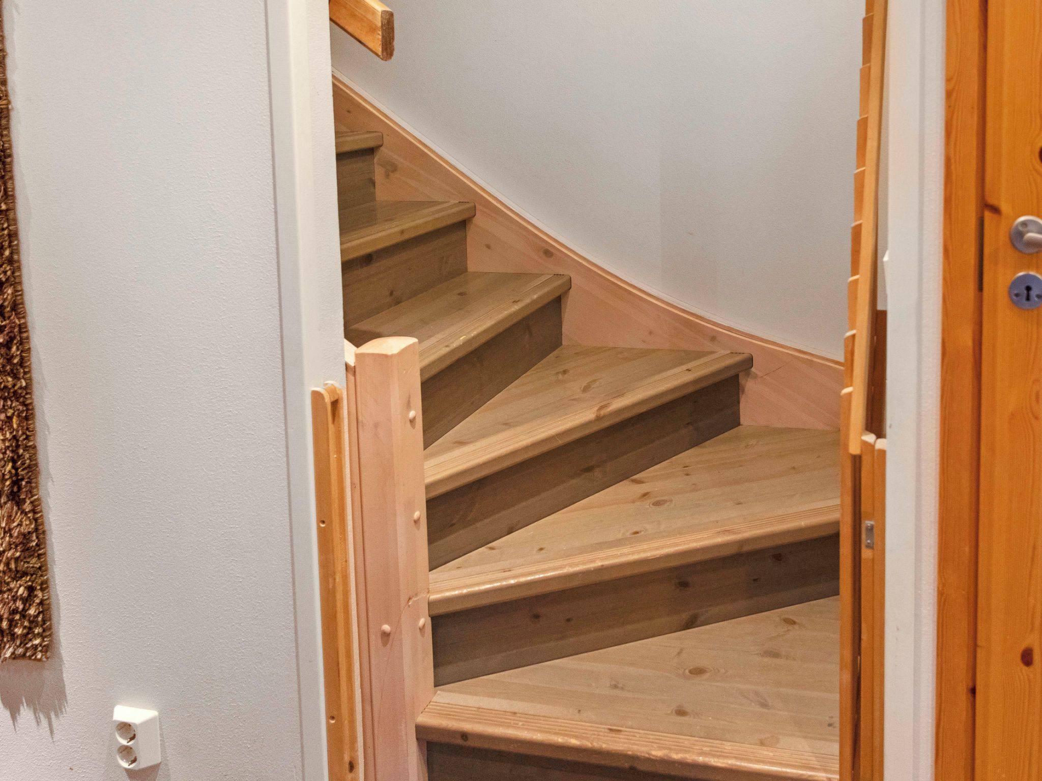 Un escalier en bois avec une rampe, menant à l’étage supérieur.