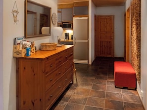 Una cocina con un armario de madera, un microondas y un refrigerador.