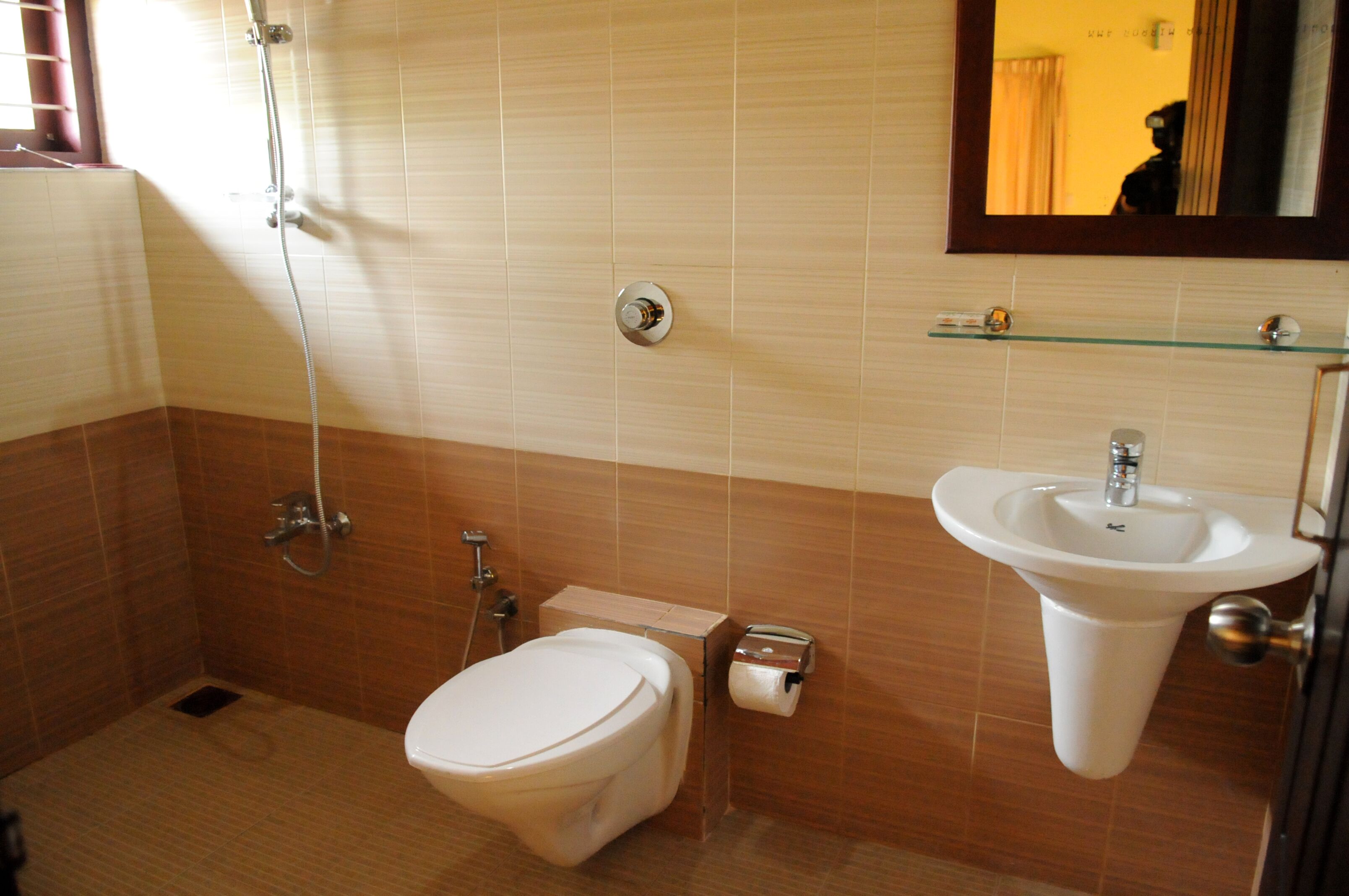 Ein Badezimmer mit Toilette, Waschbecken, Dusche und Ablagefläche aus Glas darüber.