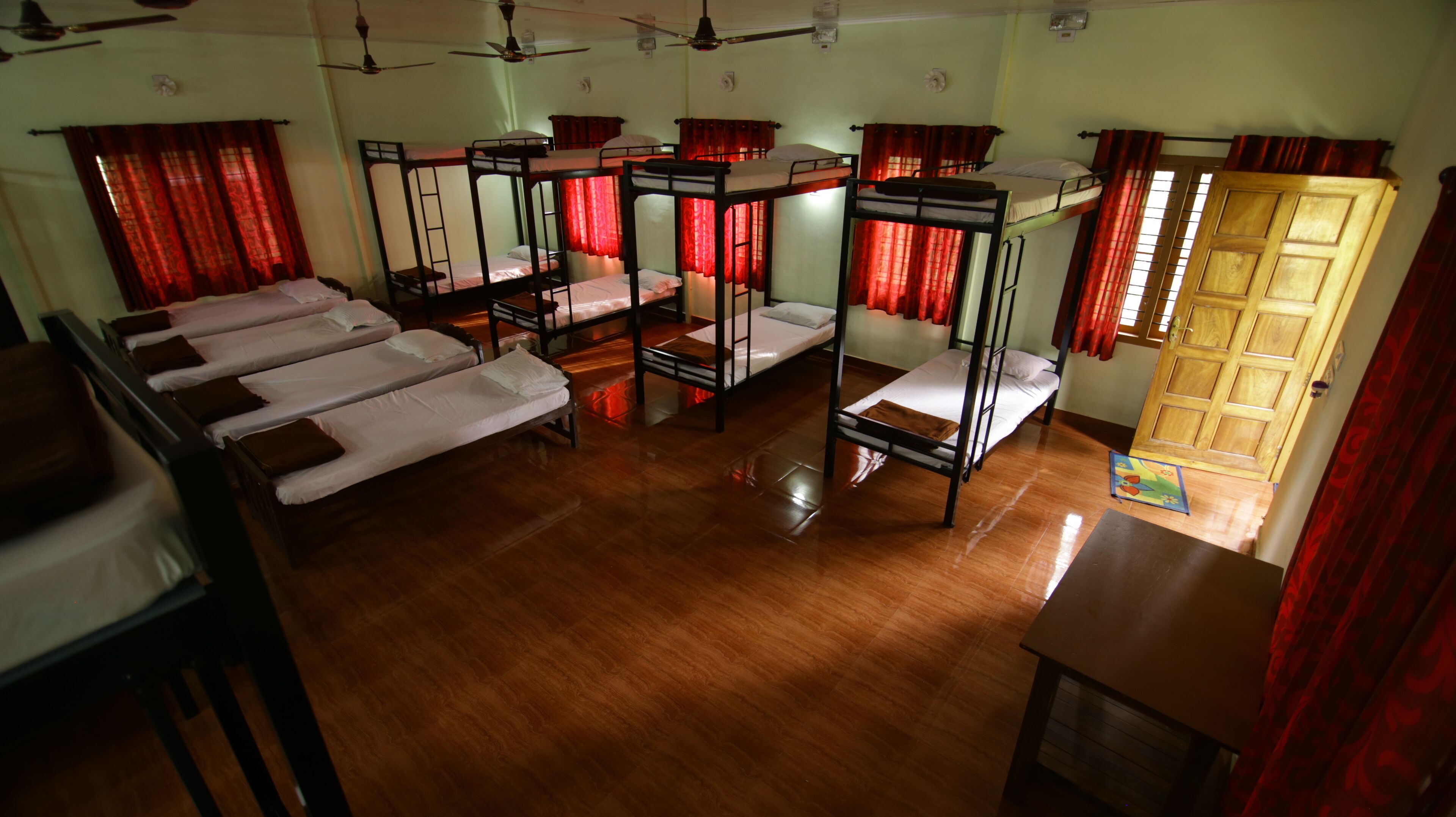 Un dormitorio con literas, piso de madera y cortinas rojas.